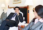 Businessman talking on the telephone with a businesswoman sitting in front of him