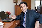 Portrait of a businessman sitting in front of a laptop and smiling