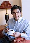 Portrait d'un jeune homme tenant une tasse de thé et souriant