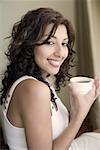 Portrait of a young woman holding a cup of tea and smiling