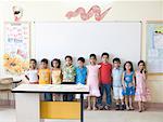 Écoliers et écolières debout côte à côte dans une salle de classe