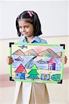 Close-up of a schoolgirl holding a painting and smiling