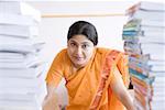 Portrait of a female teacher standing between a stacks of books
