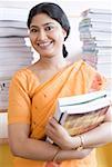 Portrait of a female teacher holding books and smiling in a library
