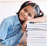 Portrait of a schoolgirl leaning over a stack of books and smiling