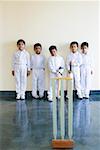 Portrait of five boys standing behind cricket stumps