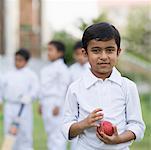 Portrait of a boy holding a cricket ball and smiling