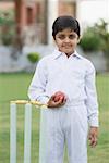 Portrait of a boy holding a cricket ball and smiling