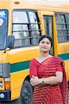Portrait of a teacher standing near a school bus