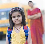 Portrait of a girl standing on the road with her teacher standing in the background