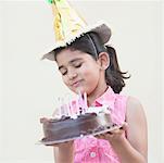 Close-up of a girl holding a birthday cake and smiling