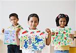 Two schoolboys with a schoolgirl holding their paintings