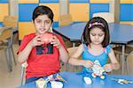 Two students making paper craft products in a classroom