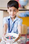 Portrait of a schoolboy holding candies in a bowl