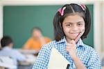 Portrait d'une écolière de tenir un crayon avec un livre et souriant