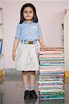 Portrait of a schoolgirl standing near a stack of books
