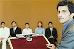 Portrait of a businessman at a lectern with his colleagues in the background