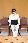 Portrait of a businessman sitting on a chair and using a laptop