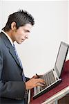 Side profile of a businessman using a laptop at a lectern