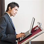 Seitenansicht eines Unternehmers mit einem Laptop auf ein Pult