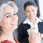 Portrait of two businesswomen holding cups of tea and smiling