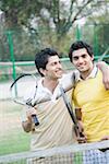Zwei junge Männer Tennisschläger in einem Gericht zu halten und Lächeln