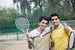 Porträt von zwei jungen Männern holding Tennisschläger und Lächeln