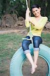 Portrait of a young woman swinging on a tire swing