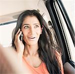 Close-up of a young woman talking on a mobile phone and traveling in a car