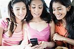 Close-up of three young women looking at a mobile phone and smiling