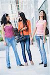 Drei junge Frauen tragen ihre Handtaschen und Lächeln