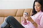 Gros plan d'une jeune femme assise sur un canapé et d'un téléphone mobile