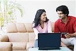 Jeune couple achats en ligne avec une carte de crédit et regarder les uns les autres