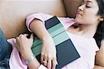 High angle view of a young woman sleeping on a couch with a book