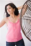 Young woman standing in front of an electric fan