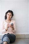 Jeune femme contre un mur et d'un téléphone portable
