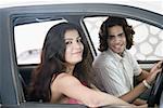 Seitenansicht eines jungen Paares in einem Auto sitzen und Lächeln