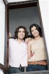 Portrait of a young couple looking through a window and smiling