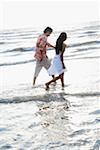 Side profile of a young woman walking on the beach with a young man