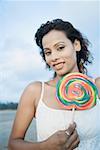 Portrait d'une jeune femme tenant un bonbon et souriant