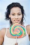Portrait of a young woman holding a candy and smiling