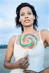 Close-up of a young woman standing and holding a lollipop