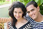 Portrait of a young man with his arm around a young woman and smiling