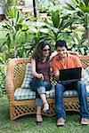 Young man sitting on a couch with a young woman and using a laptop