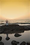 Femme méditant sur la plage au crépuscule