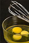 Close-up of egg yolks in a glass bowl with an egg beater