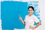 Portrait of a young woman painting a wall and smiling