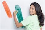 Portrait of a young woman painting the Indian flag on a wall and smiling