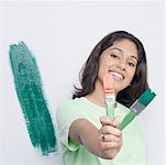 Portrait of a young woman showing two paint brushes and smiling