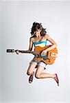 Jeune femme jouant une guitare et en sautant